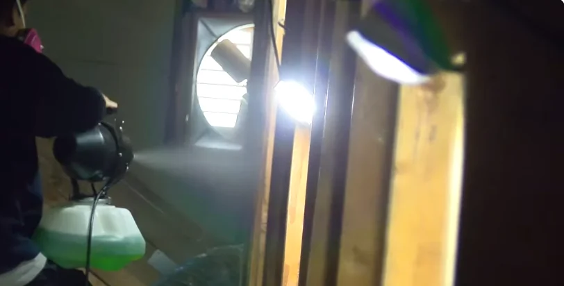 Technician spraying disinfectant across an attic after rodent removal