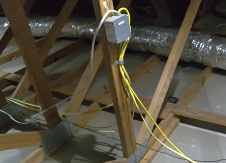 Exposed electrical wiring across attic joists, the kind rodents often chew