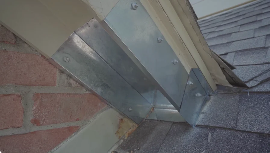 Sheet metal flashing installed where a roof meets a brick wall to keep roof rats out
