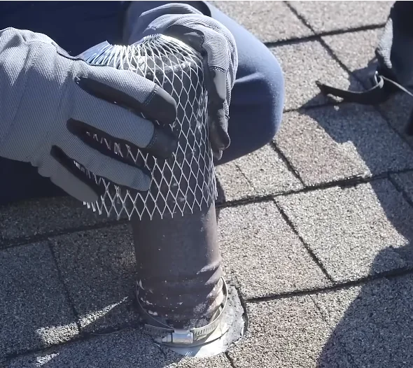 Mesh guard being fitted over a roof plumbing vent pipe