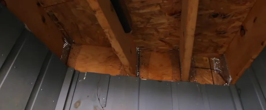 Hardware cloth closing an old soffit corner gap on a raised wood-frame house